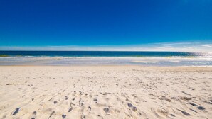 Una playa arenosa con huellas que van hacia el agua.