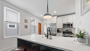 A modern kitchen with white cabinets, stainless steel appliances, and a large island with bar stools.