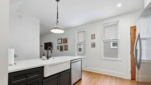 A modern kitchen with a white countertop, dark cabinets, and a stainless steel refrigerator.