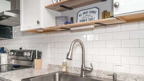 A modern kitchen with a stainless steel sink, a built-in oven, and a dish soap pump.