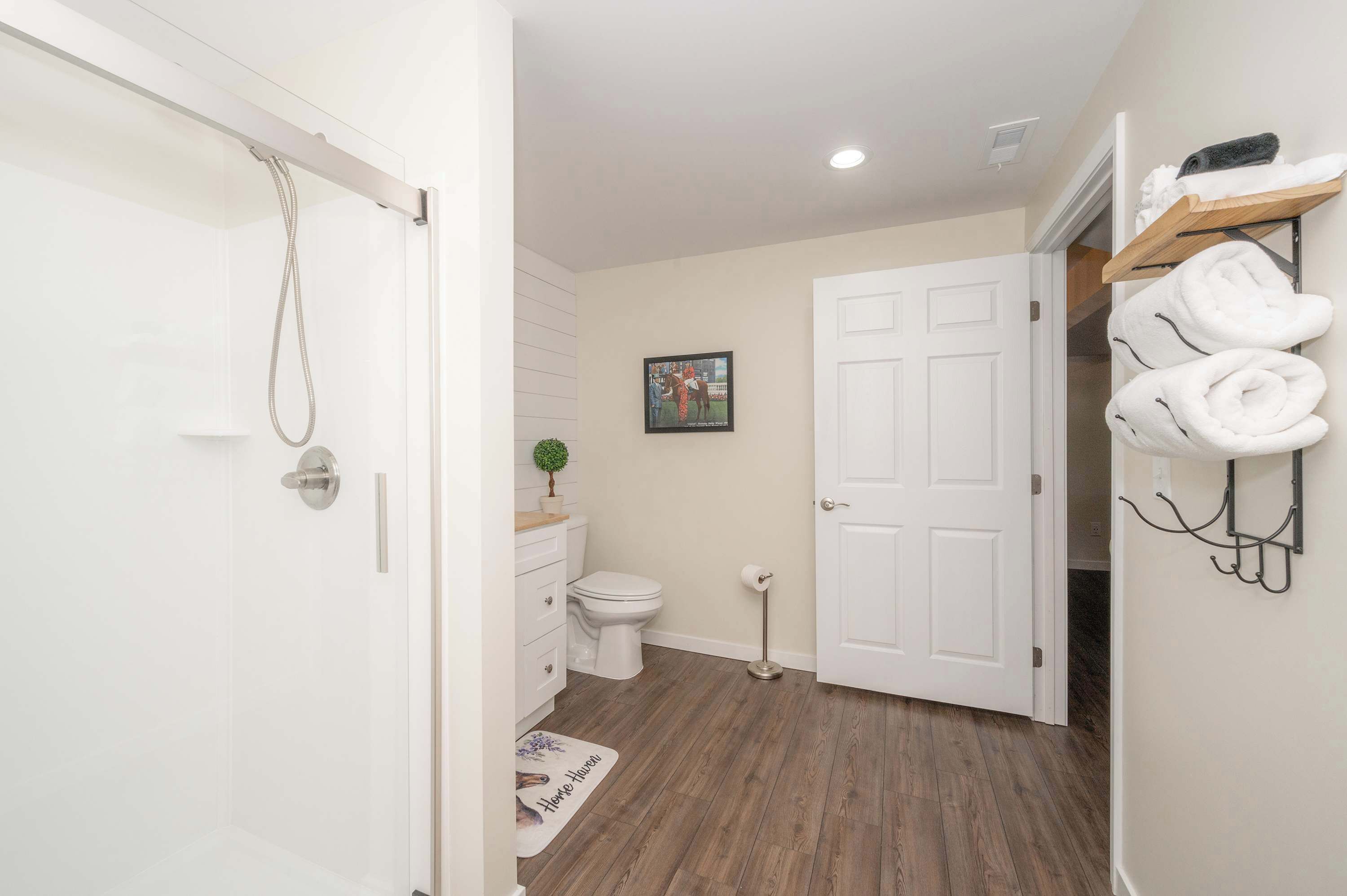 A bathroom with a shower, toilet, and a towel rack.