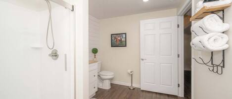A bathroom with a shower, toilet, and a towel rack.