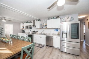 A modern kitchen with white cabinetry, stainless steel appliances, and a wooden dining table. - Arkstone Retreat - 3 in 1! Only 4 min to the Ark! (Williamstown)