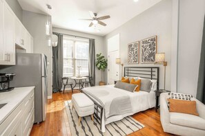 A modern bedroom with a bed, bedside tables, a desk, and a chair. - Findlay Market Suites – 4 in 1! (Cincinnati)