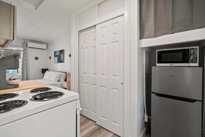 A compact kitchen with a stove, microwave, and refrigerator. - Chic Studio | Near Franklin Park + Downtown (Columbus)