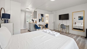 Ein Hotelzimmer mit einem großen Bett, einem Schreibtisch, zwei Stühlen, einem Fernseher und einem Spiegel.