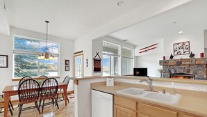 A modern kitchen with a dishwasher, wooden cabinets, and a stone fireplace.
