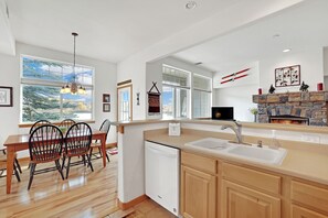 A modern kitchen with a dishwasher, wooden cabinets, and a stone fireplace.