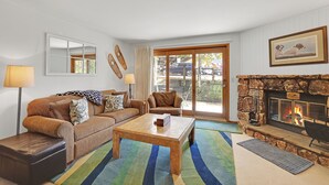 A living room with a stone fireplace, a large window, and a couch.