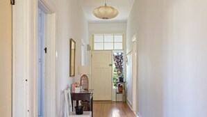 A hallway with a white door at the end, a small table with a lamp, and a chair. - Hollybrooke Cottage, prestige suburb in Launceston (East Launceston)