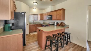 Eine Küche mit Holzausstattung, einem schwarzen Kühlschrank, einer Mikrowelle, einer Kaffeemaschine und einer Bar mit Barhocker.