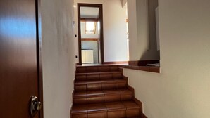 Una escalera con escalones de madera que lleva a una habitación con techo inclinado y tragaluz.