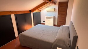 Un dormitorio con cama, armario, cómoda y aire acondicionado.