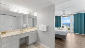 A modern hotel room with a large mirror, a double bed, a balcony with a view of the beach, and a bathroom with a sink and vanity. - NEW RENTAL! COMPLETELY RENOVATED! GREAT BEACH AND POOL VIEWS (Panama City)