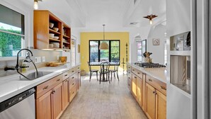 Una cocina moderna con armarios de madera, una isla central y un comedor con sillas.