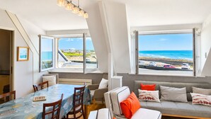 Un ambiente moderno con zona pranzo, posti a sedere e ampie finestre vista oceano.