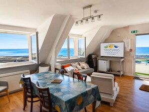 A room with a dining table, chairs, a sofa, and a TV displaying 'TIPOZ'IMMO' branding.