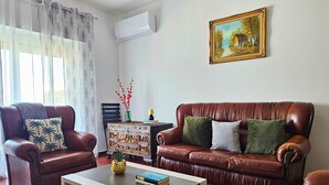 A living room with leather sofas, a coffee table, a painting, and a side table with a vase and book. - Retiro do Sol - Charming apartment in Lagos (Lagos)