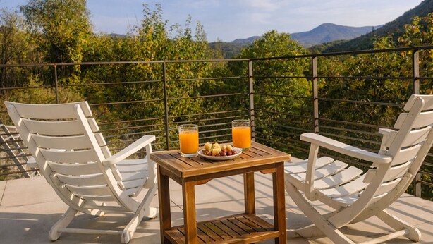 A terrace with two white chairs, a small wooden table with a plate of fruit and two glasses of orange juice, and a scenic mountain view. - Farm cottage in Gap, calm and rejuvenating (Gap)