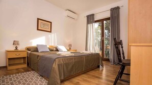Un dormitorio con cama, mesitas de noche, un escritorio y una silla.