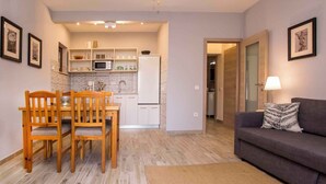 Un espacio habitable compacto con zona de comedor, kitchenette y sofá.