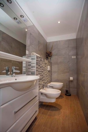 Un baño moderno con un espejo grande, lavamanos dobles y un bidé.