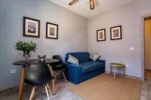 Una sala de estar moderna con un sofá azul, sillas negras, una mesita redonda y cuadros en la pared.