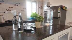 Une cuisine dotée d’un plan de travail en granit, d’un réfrigérateur en acier inoxydable, d’une plante en pot et d’un distributeur d’eau.