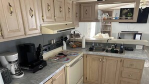 Una cocina con armarios de madera, estufa, cafetera y lavamanos.