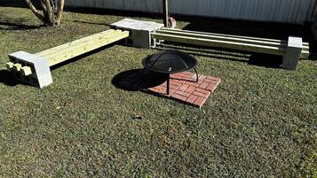 Een terras met vuurkorf, zitplaatsen en een kleine tafel.