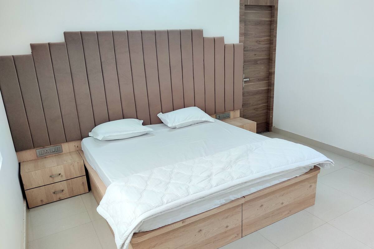 A bed with a wooden headboard, two pillows, and a white mattress.
