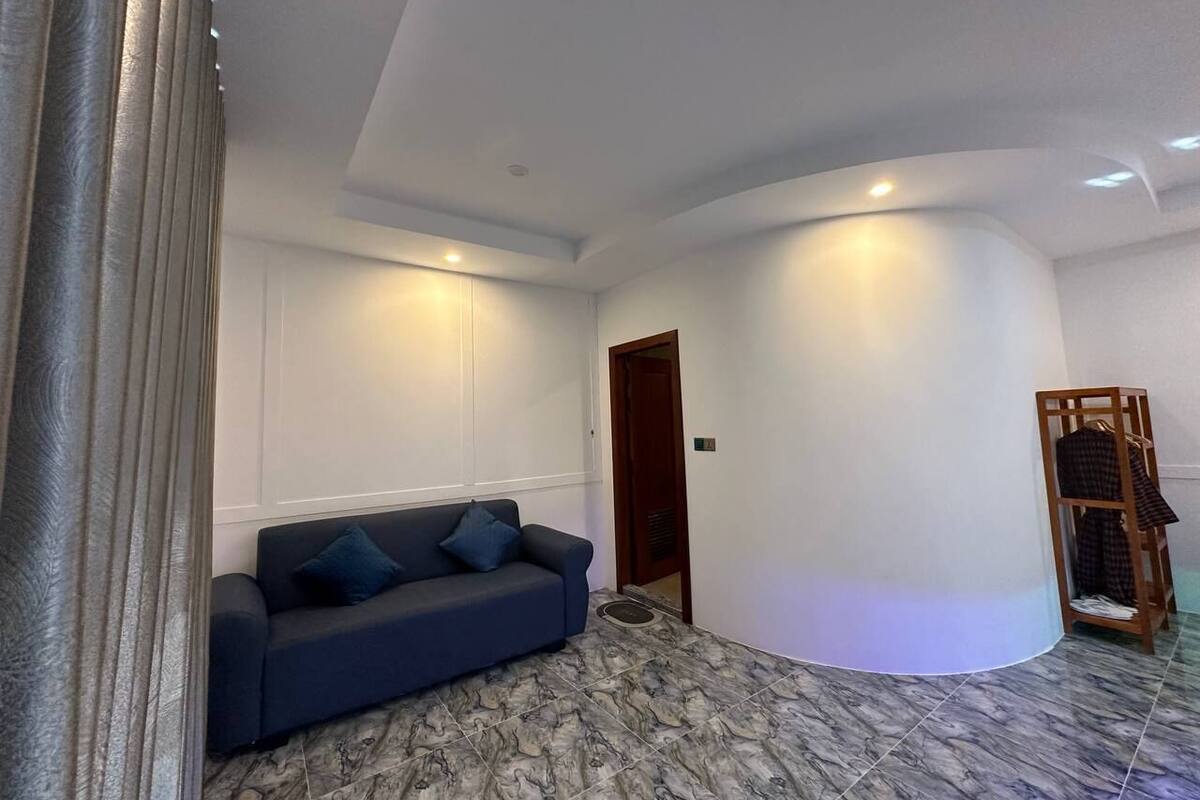 Un saló modern amb un sofà blau fosc, una porta de fusta i una petita prestatgeria amb roba.