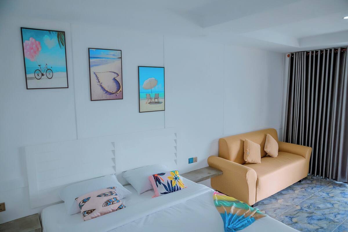 Habitació d'hotel amb un llit, un sofà i tres quadres al mur.