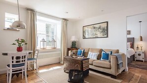 A cozy living room with a sofa, a coffee table, and a dining area with chairs. - The Pilchard Press, The Pilchard Press on Harbourside in Mevagissey Village with FREE Parking (Saint Austell)
