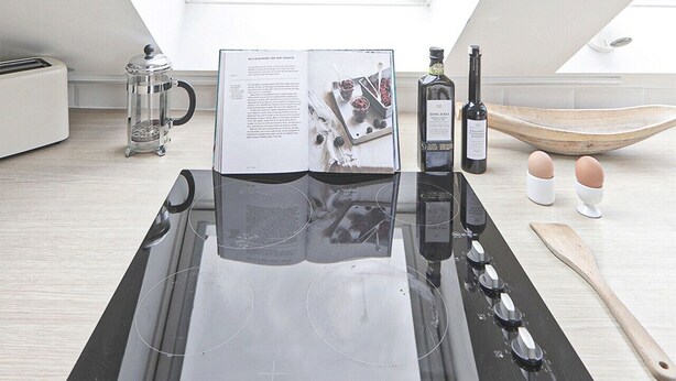 Una cocina moderna con tragaluz, cafetera, una botella de vino y una cuchara de madera sobre la encimera.