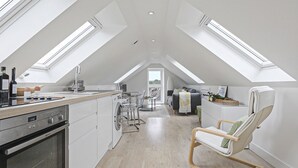 Un loft moderno con cocina, comedor y una zona de estar acogedora bajo tragaluces.