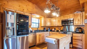 A modern kitchen with stainless steel appliances, wooden cabinets, and a wooden countertop.