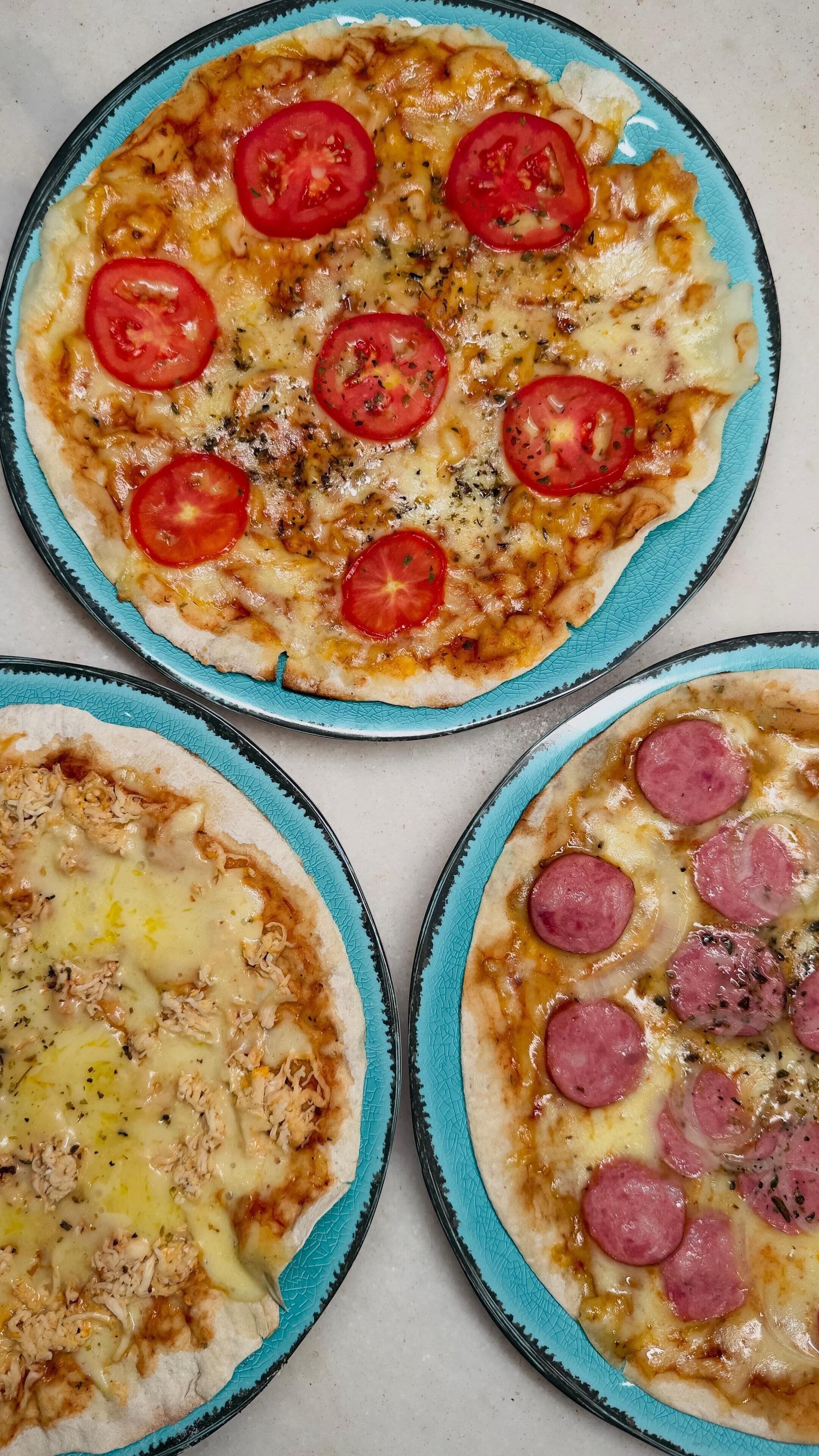 Three pizzas on plates with different toppings.