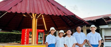 A group of people standing in front of a hotel bar with a red roof and a sign that reads "GAL HOTEL BAR".
