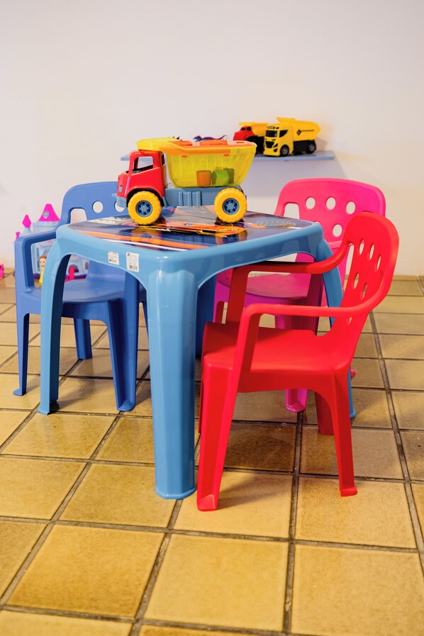 Una mesa infantil con sillas de plástico de colores y vehículos de juguete.