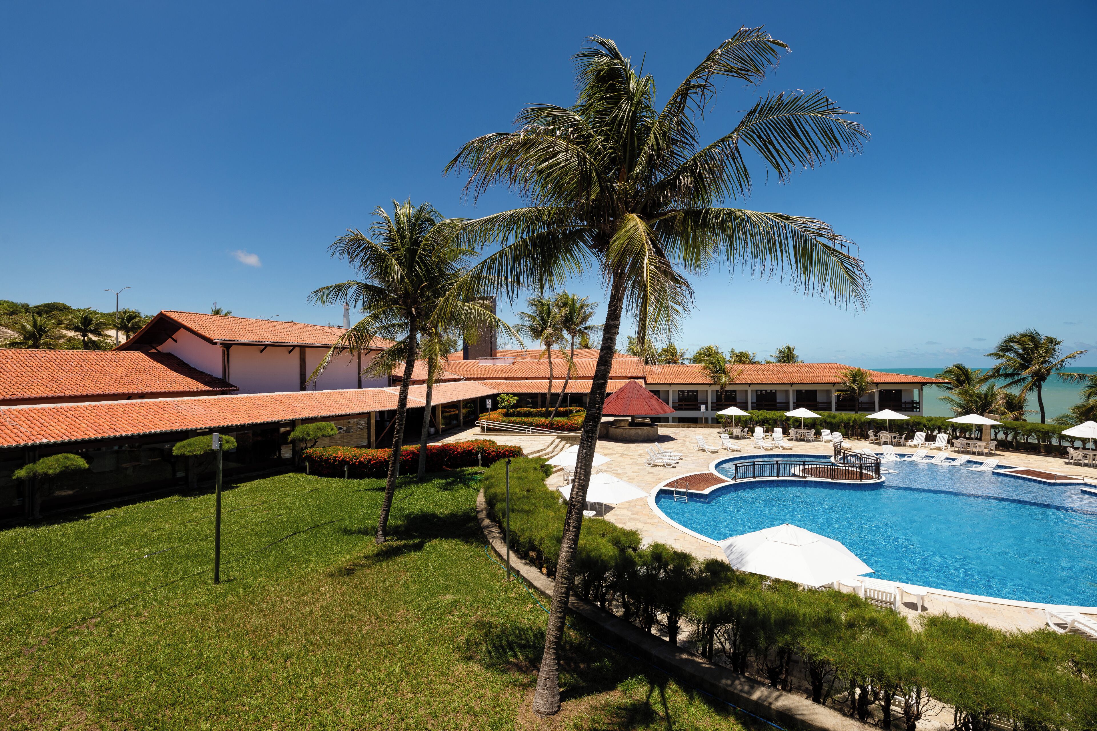 Un resort con piscina, palmeras y vista al océano.