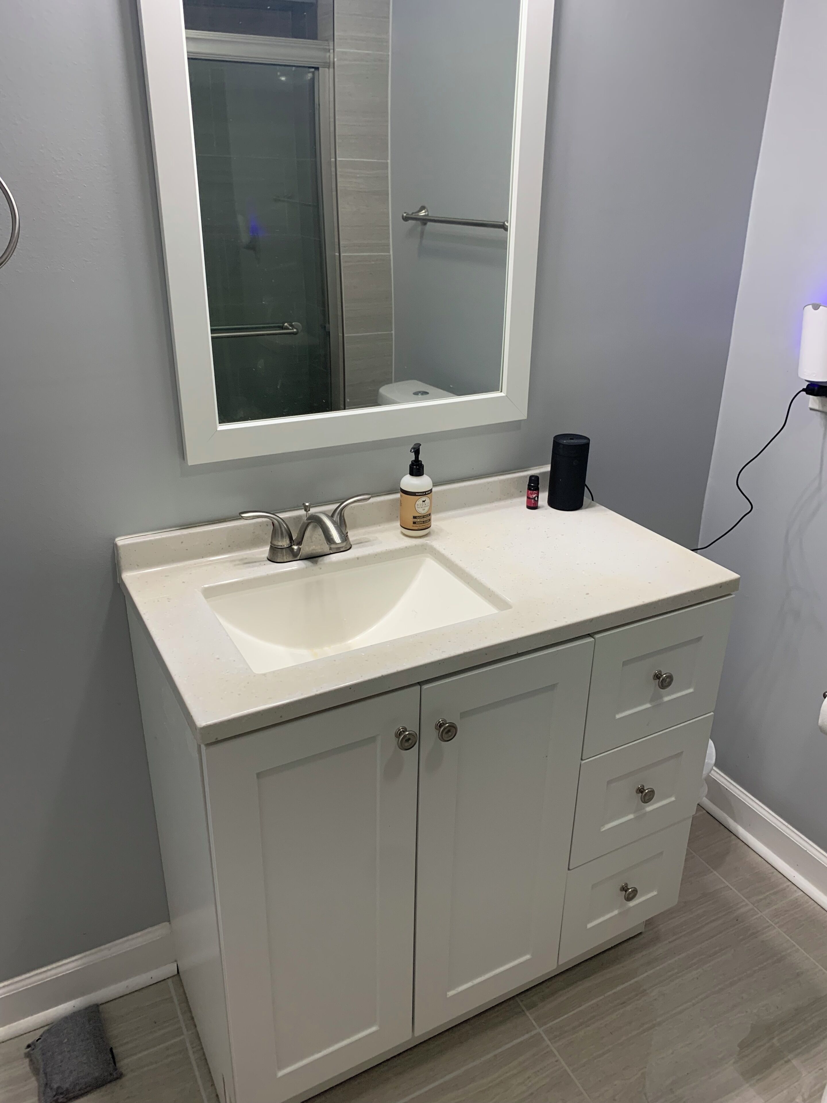 A bathroom with a white sink, a large mirror, and a cabinet with drawers.