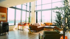 A spacious living room with a large window, a sofa, a coffee table, and a plant.
