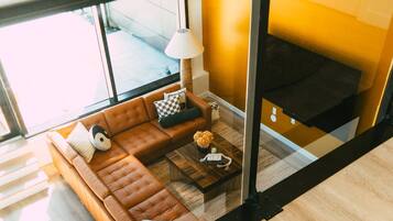 Un salon moderne avec un canapé en cuir marron, une table basse en verre et une lampe.