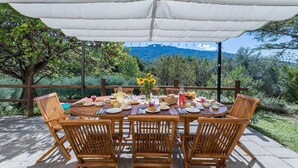 An outdoor dining area with a table set for four, surrounded by wooden chairs, under a white canopy. - Casa Pippin 8, Emma Villas (Cortona)