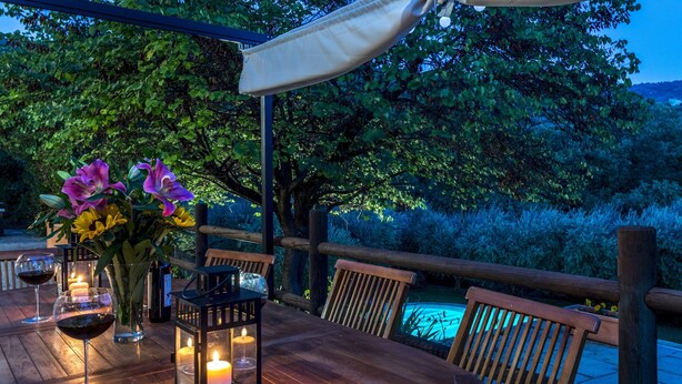 An outdoor dining area with a wooden table, chairs, candles, and a lantern. - Casa Pippin 8, Emma Villas (Cortona)