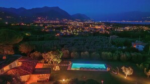 Een groot resort met een zwembad, meerdere gastenkamers en uitzicht op een stadsbeeld en bergen op de achtergrond.