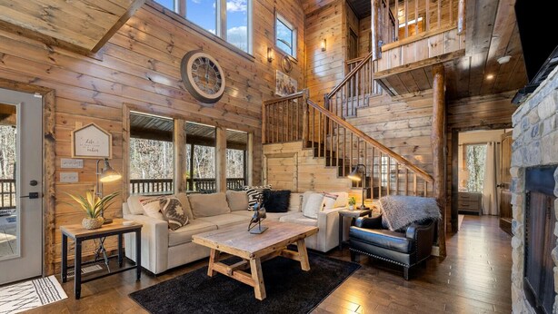A spacious living area with a wooden interior, a staircase, and a fireplace. - SkyHorse Lodge (direct access to national forest) 3 bedroom, 3.5 bath (Broken Bow)