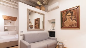 A modern room with a grey sofa, a bed, a mirror, and two framed pictures on the wall. - Brera Apartments in Arena (Milan)