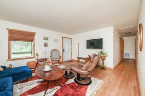 A living room with a sofa, a leather chair, a coffee table, and a TV.